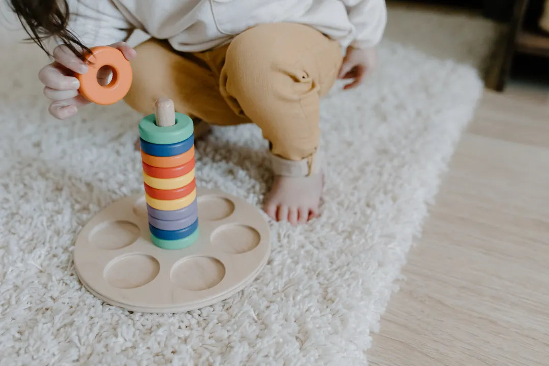 木のリングを積んで遊ぶ子どもの手元