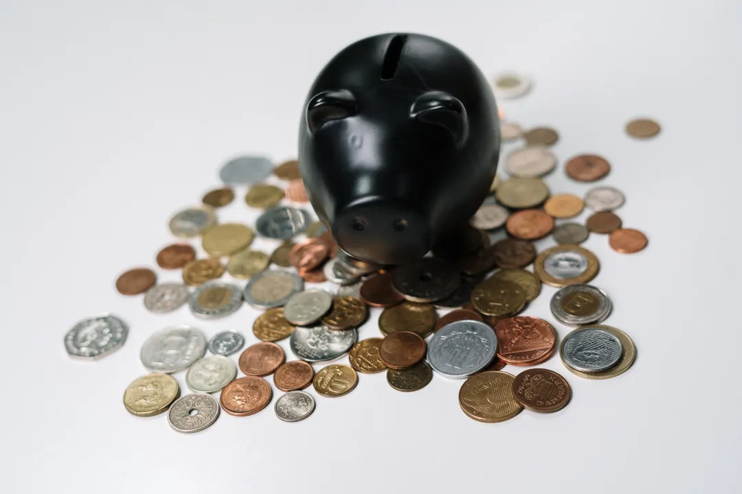 白い机に置かれた貯金箱と硬貨