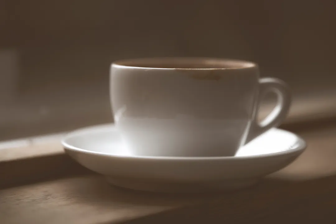 窓辺に置かれた白いコーヒーカップ